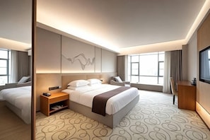Ein modernes Hotelzimmer mit einem großen Bett, Nachttischen, einem Schreibtisch und einem Fernseher.