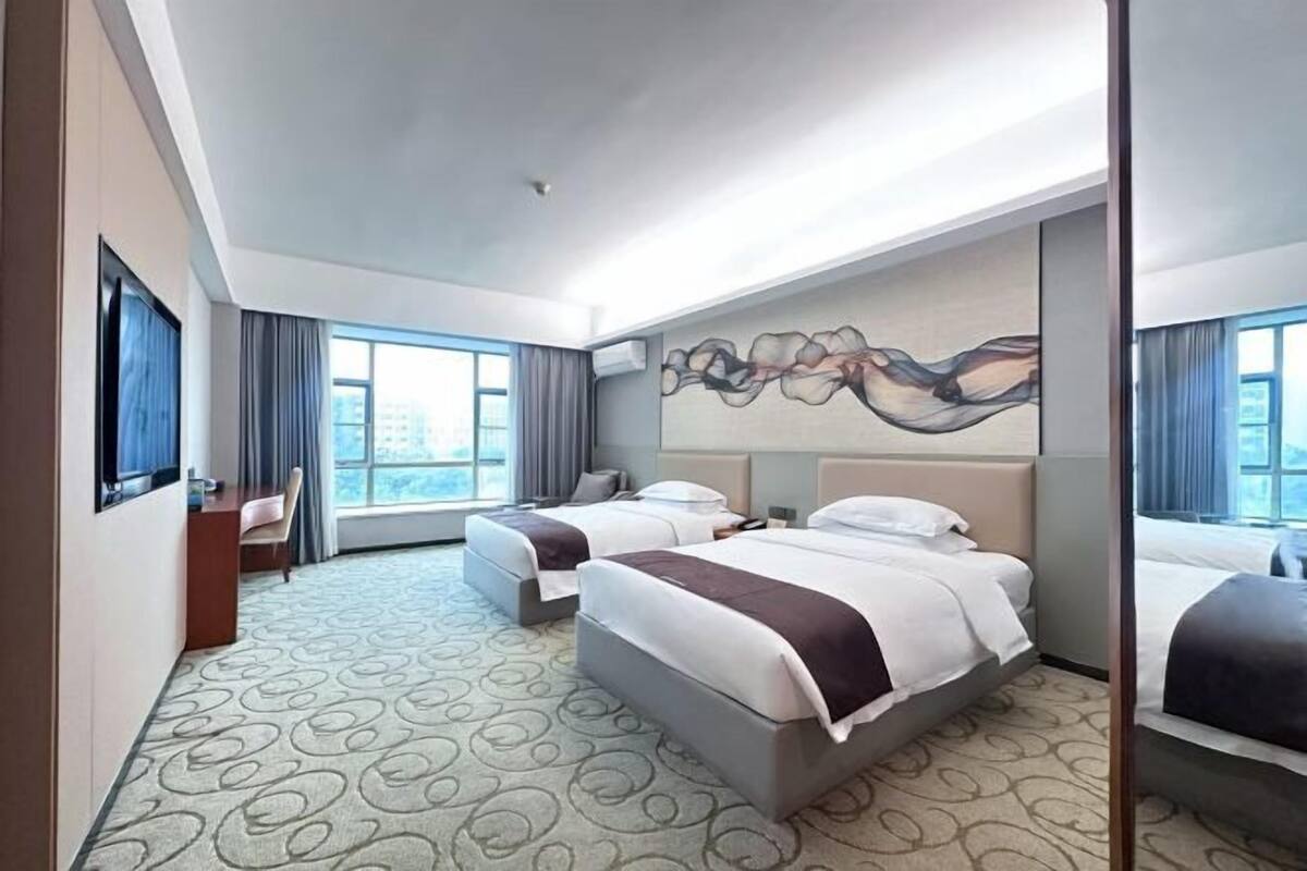 Une chambre d’hôtel avec deux lits, un bureau et une grande fenêtre.