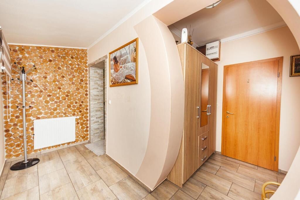 A bathroom with a stone wall, a radiator, a shower, and a wooden cabinet.