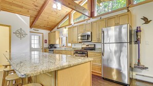 Cuina amb armaris de fusta, electrodomèstics d'acer inoxidable i taulell de granat.