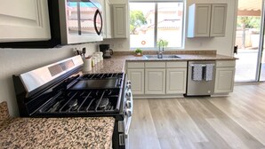 Una cocina moderna con armarios blancos, encimera de granito, estufa integrada y lavavajillas.