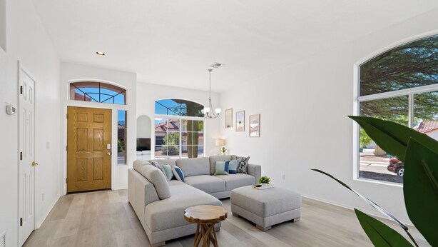 Un salón espacioso con un sofá modular grande, una mesa de centro redonda de madera y vistas a través de un ventanal.