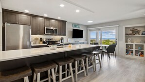 A modern kitchen with a large island, bar stools, and a view of the beach. - Seashell Dunes - Oceanfront, Beach Access, Pool (Fernandina Beach)