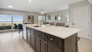 A kitchen with a large island, dark cabinets, and a view of the beach. - Seashell Dunes - Oceanfront, Beach Access, Pool (Fernandina Beach)