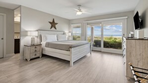 A bedroom with a bed, a star decoration, a ceiling fan, a TV, and a view of the beach. - Seashell Dunes - Oceanfront, Beach Access, Pool (Fernandina Beach)