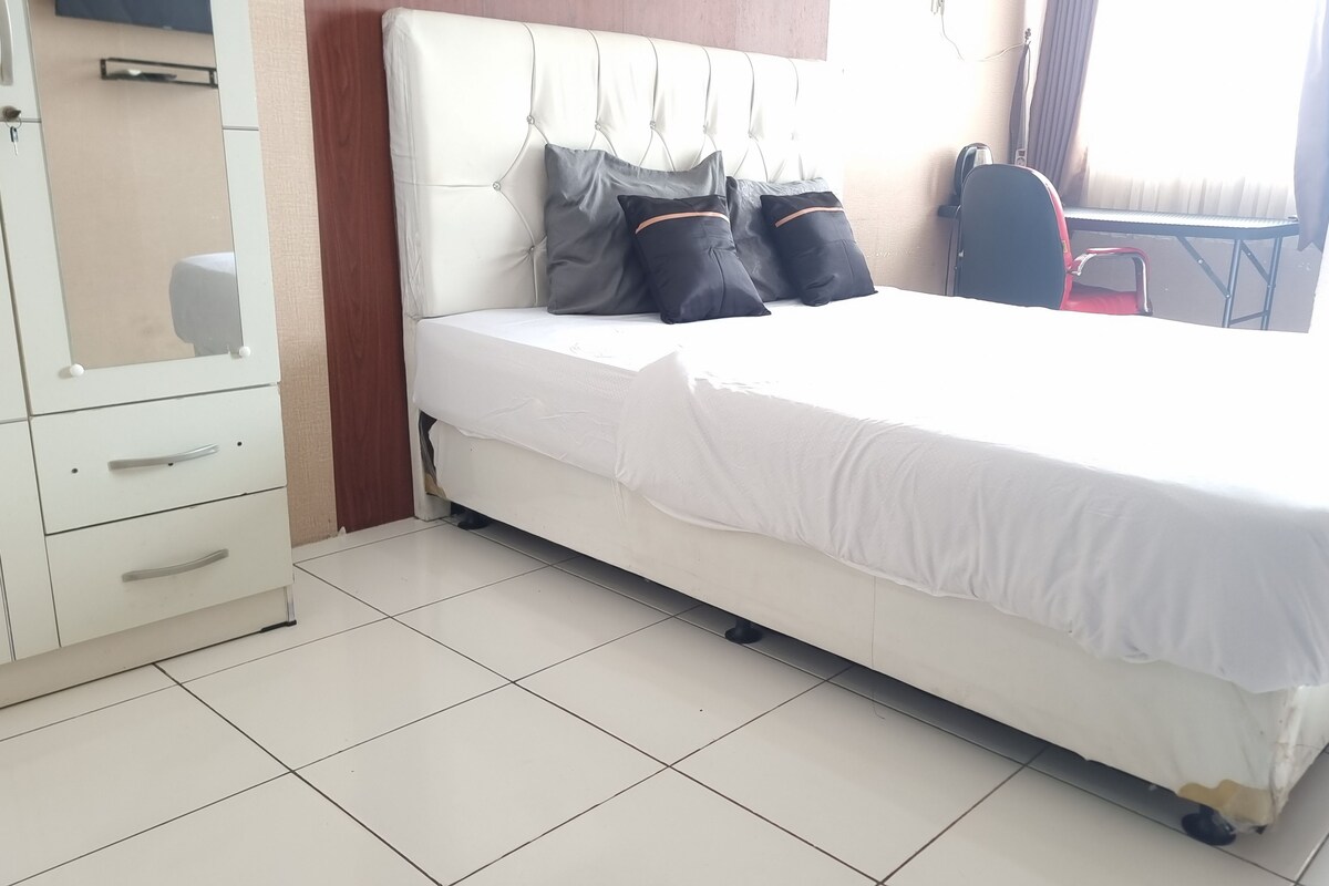 Une chambre d’hôtel avec un lit blanc, une armoire et une chaise.