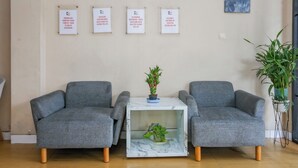 Une pièce comprenant deux fauteuils gris, une petite table avec une plante et quatre panneaux encadrés accrochés au mur.