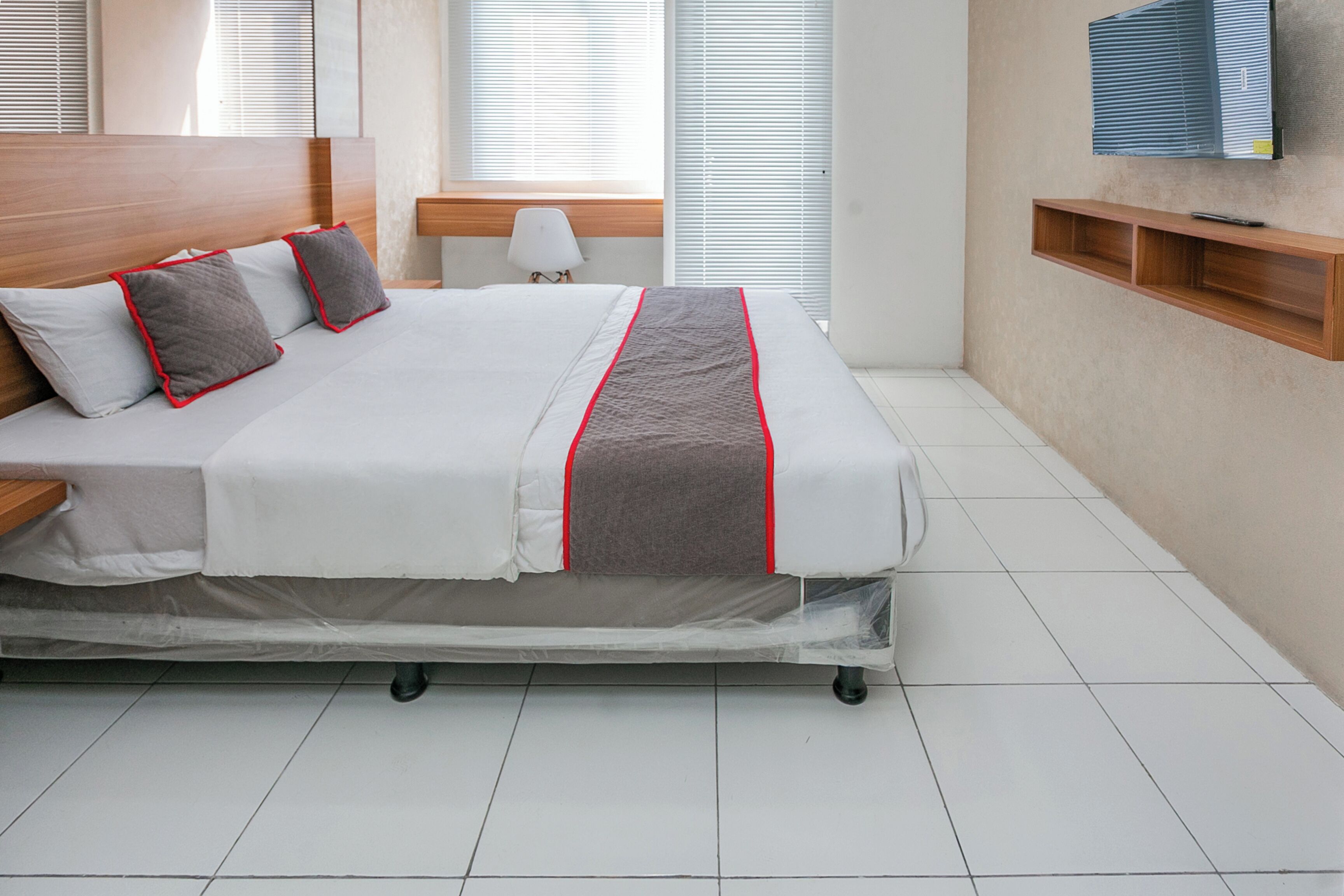 A neatly made bed with a grey and white duvet, a wooden headboard, and a bedside table with a lamp.