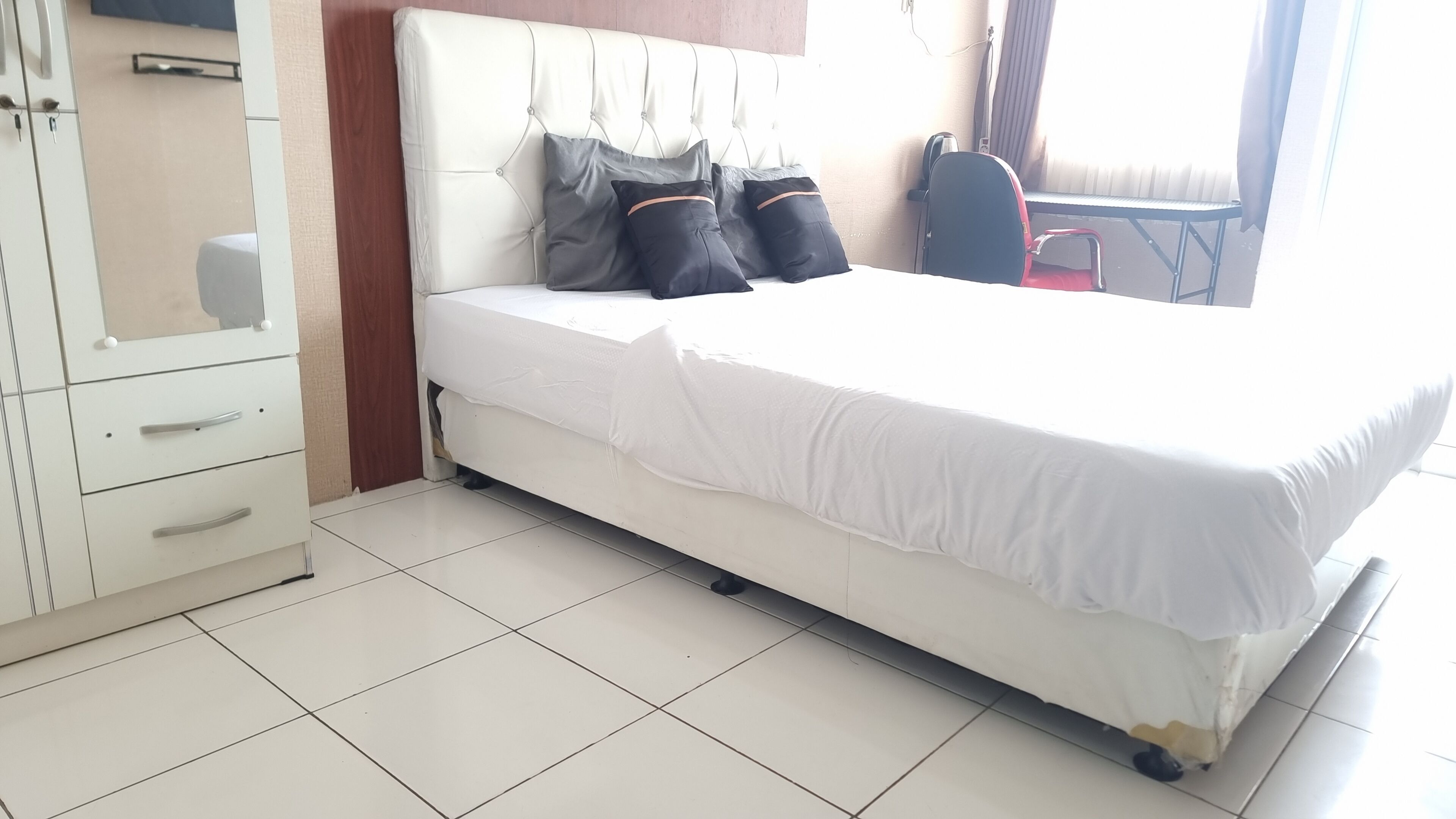 Habitación de hotel con una cama blanca, un armario y una silla.