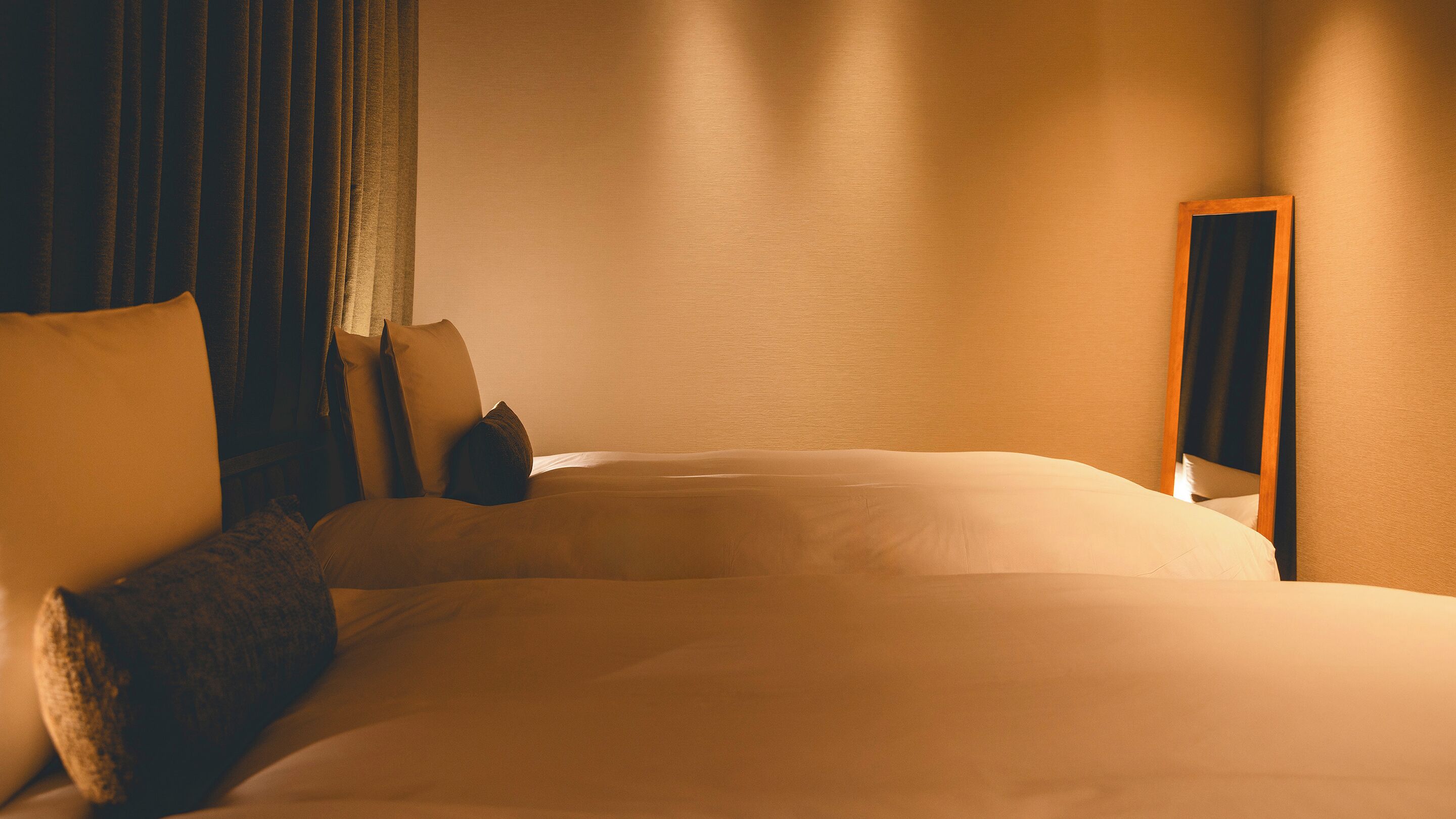A hotel room with a large bed, a bedside table, and a mirror.