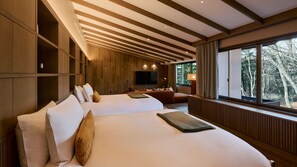 Une chambre d’hôtel moderne dotée d’un grand lit, d’un canapé, d’une télévision et d’une fenêtre donnant sur la verdure.