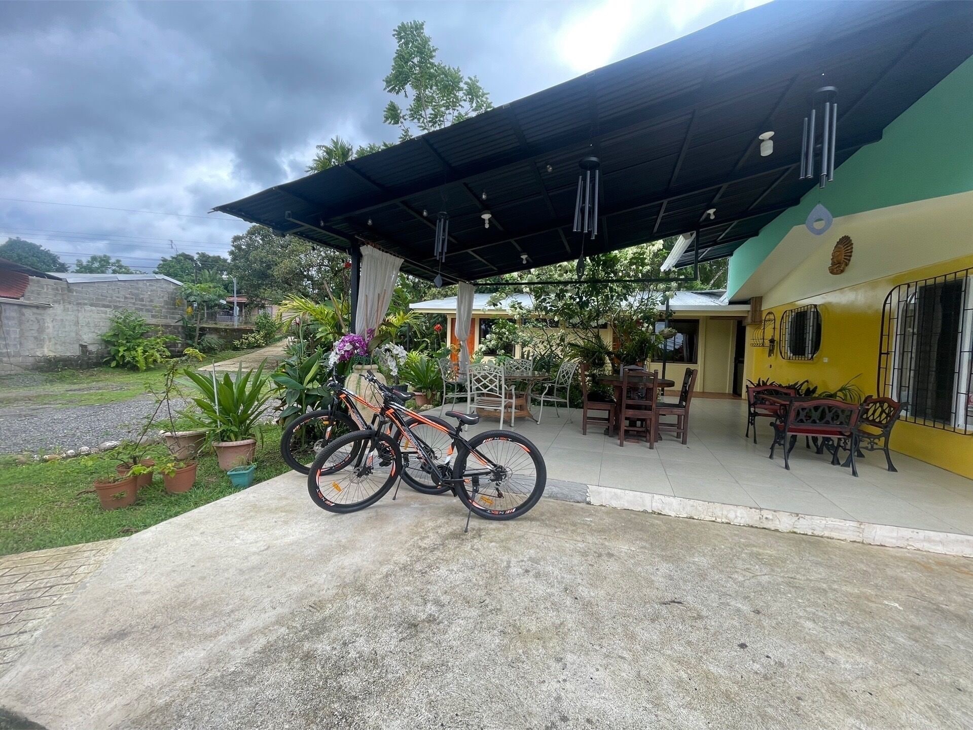 Un patio techado con mobiliario exterior, una bicicleta y plantas en macetas.