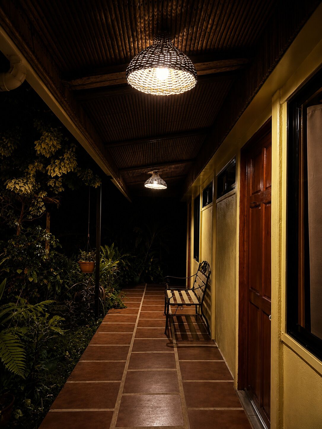 A corridor with a bench, a hanging light fixture, and a door.