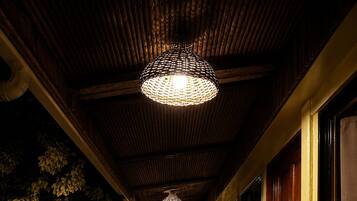 A corridor with a bench, a hanging light fixture, and a door.
