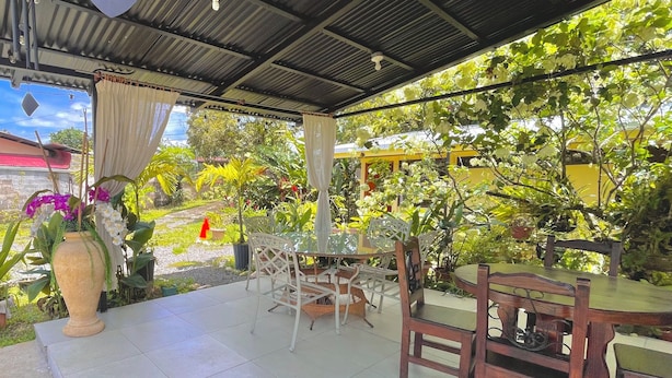Un espace extérieur aménagé en terrasse, doté d’un sol carrelé, de chaises en osier blanc et d’une table en bois.