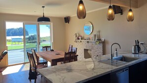 A modern kitchen with a marble island, pendant lights, and a view of the outdoors.