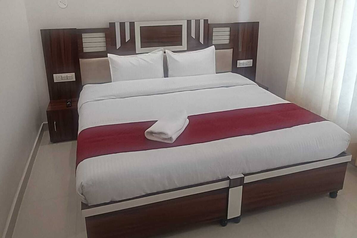 A neatly made bed with a white and red bedspread, wooden headboard, and bedside tables with lamps.
