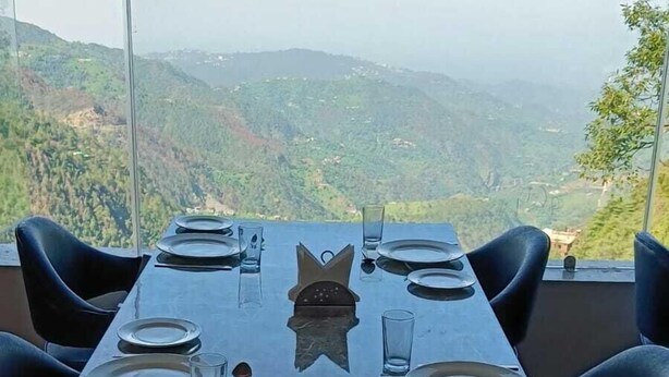 A dining table set for four with a view of a mountainous landscape. - Barowalia Villa (Dalhousie)