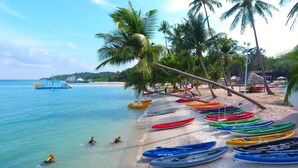 A beach with rows of colorful kayaks and a large ship in the background. - Kepri Coral Resort (Galang)