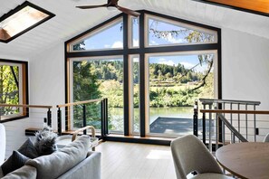 Ein modernes Interieur mit großen Fenstern, die Blick auf einen See und Wald gewähren.