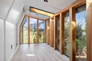 Ein modernes Interieur mit großen Fenstern, Holzbalken und einem hellen Boden.