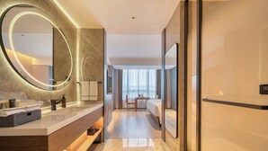 A modern hotel room with a large mirror, a wooden vanity, a bed, and a view of the city through large windows. - UrCove by Hyatt Hangzhou North Grand Canal (Hangzhou)