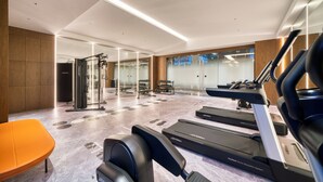 A modern gym with treadmills, a weight bench, and a glass wall leading to a hallway. - UrCove by Hyatt Hangzhou North Grand Canal (Hangzhou)