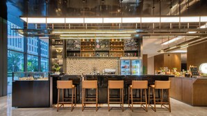 A modern bar area with a marble countertop, wooden stools, and a variety of bottles. - UrCove by Hyatt Hangzhou North Grand Canal (Hangzhou)