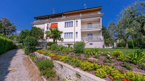 Un immeuble à plusieurs étages doté de balcons, entouré d’un jardin aménagé avec différentes plantes et fleurs.