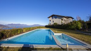 Una casa moderna amb piscina, envoltada de vegetació i una vista despejada de muntanyes.