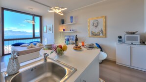Una cuina moderna amb un gran finestral, un rentaplat i una zona de menjador amb taula per a dues persones.