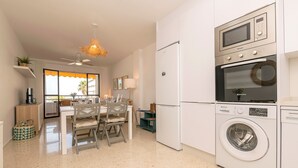 A modern kitchen with a built-in washer and dryer, a dining area with a table and chairs, and a ceiling fan. - Ventana A Do ana in Sanlucar de Barrameda (Sanlucar de Barrameda)