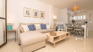 A modern living room with a sofa, coffee table, and dining area. There are framed pictures on the wall, a lamp, and a ceiling fan. - Ventana A Do ana in Sanlucar de Barrameda (Sanlucar de Barrameda)