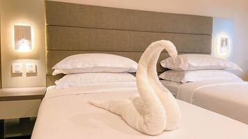 A hotel room with a neatly made bed, two pillows, and a swan-shaped towel centerpiece.