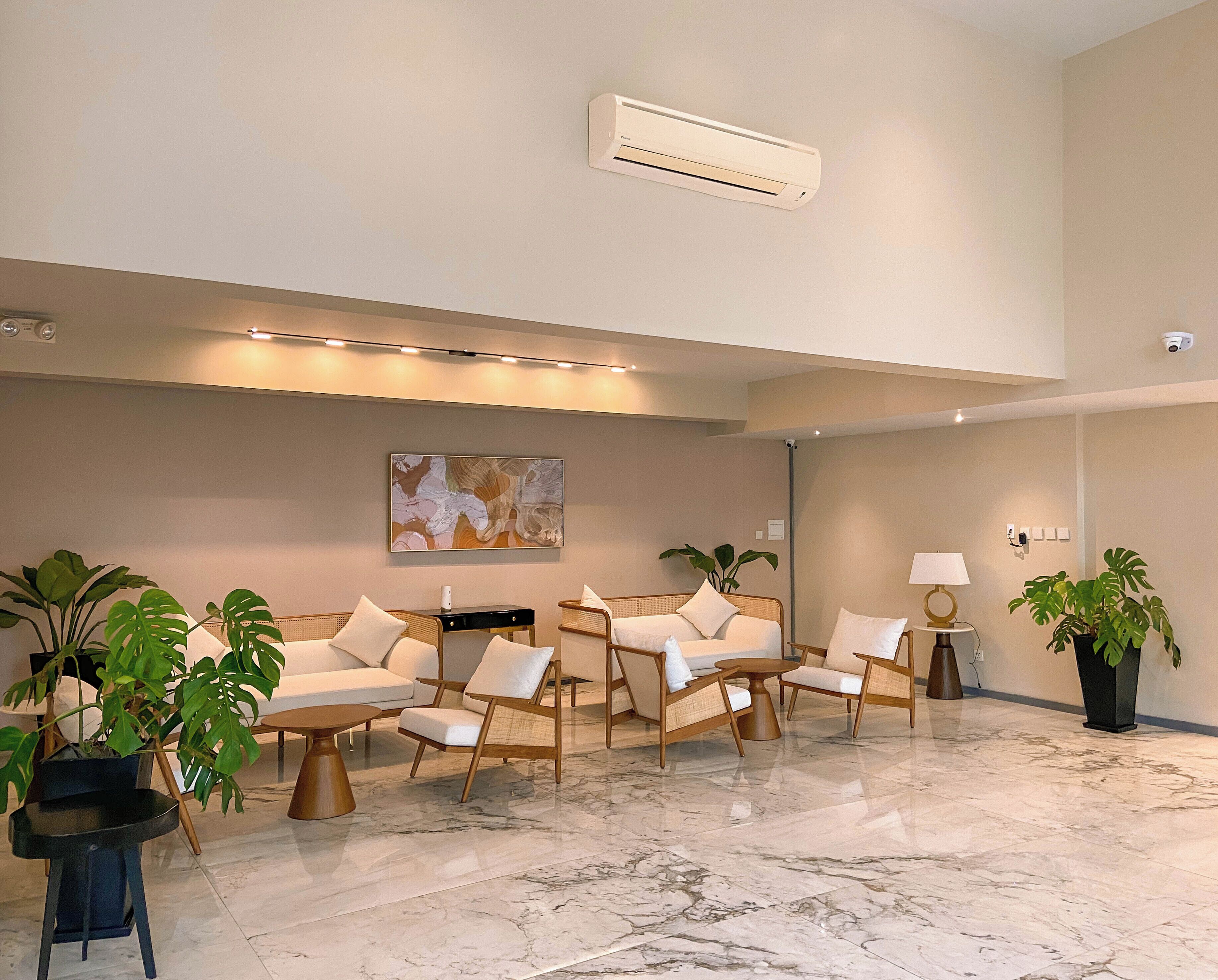 A spacious lobby with a marble floor, comfortable seating, and potted plants.