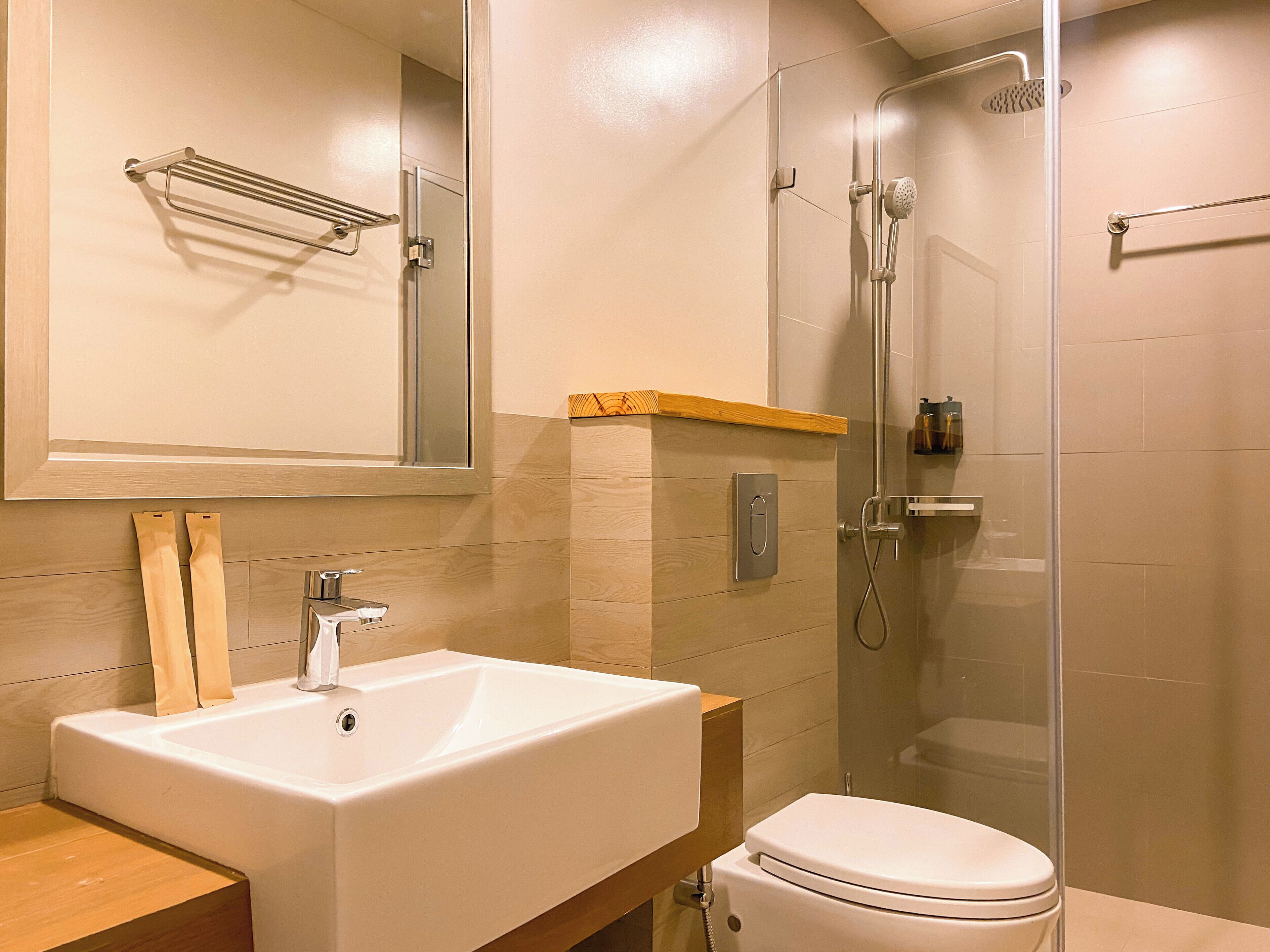 A modern bathroom with a large sink, toilet, and glass-enclosed shower.