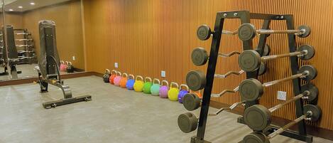Een sportschool met gewichthefapparatuur, waaronder een squatrek en kettlebells.