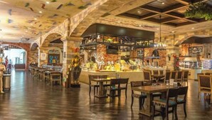 An interior with a high ceiling, stone arches, and a central bar area with seating. - Knight's Hotel Europark Resort (Qihe County)