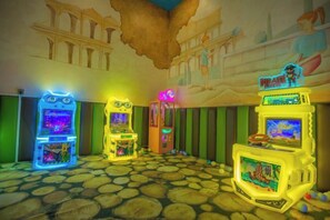 A room with arcade machines, a mural, and a patterned floor. - Knight's Hotel Europark Resort (Qihe County)