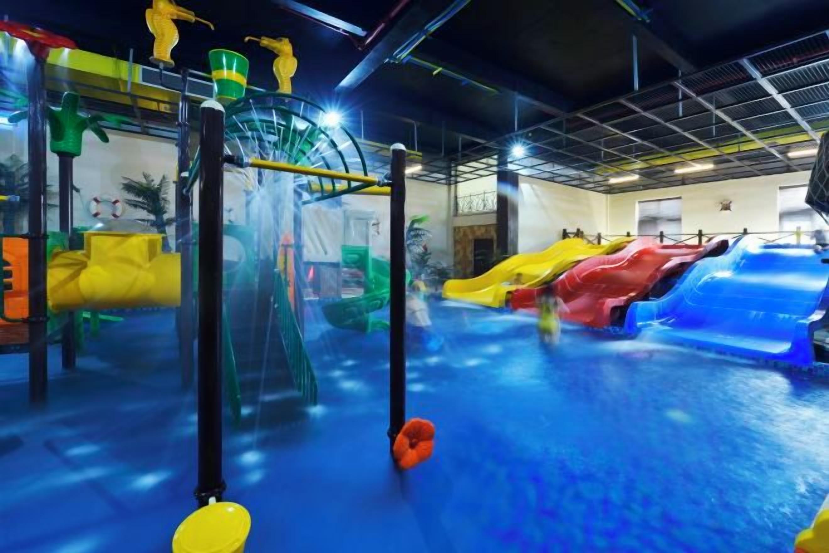 An indoor water play area with slides and climbing structures.