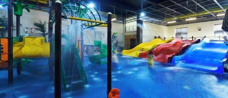 An indoor water play area with slides and climbing structures.