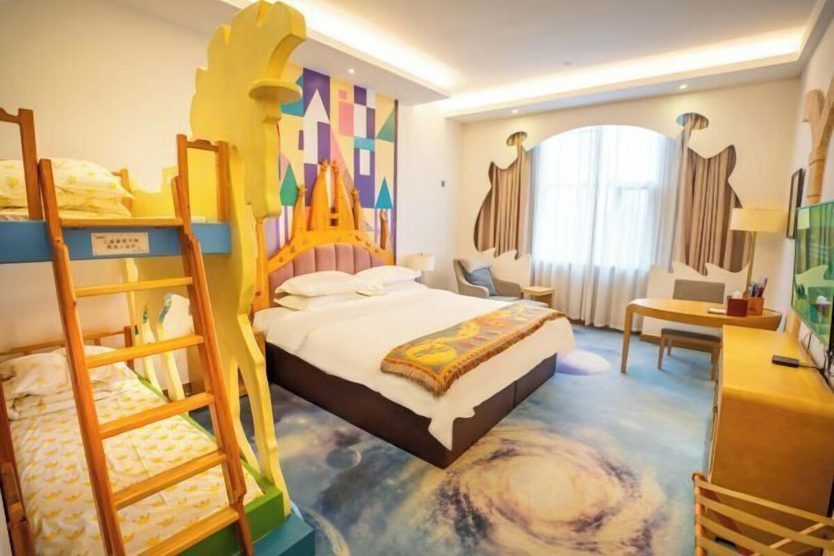 Ein Hotelzimmer mit Etagenbetten, einem Schreibtisch, einem Stuhl und einem großen Fenster mit Vorhängen.