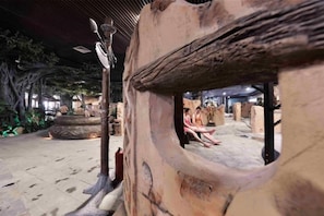 Un intérieur rustique avec une arche en pierre, un grand pot et un poteau en bois.
