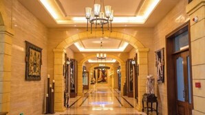 A hotel corridor with a marble floor, chandeliers, and framed artwork on the walls. - Knight's Hotel Europark Resort (Qihe County)