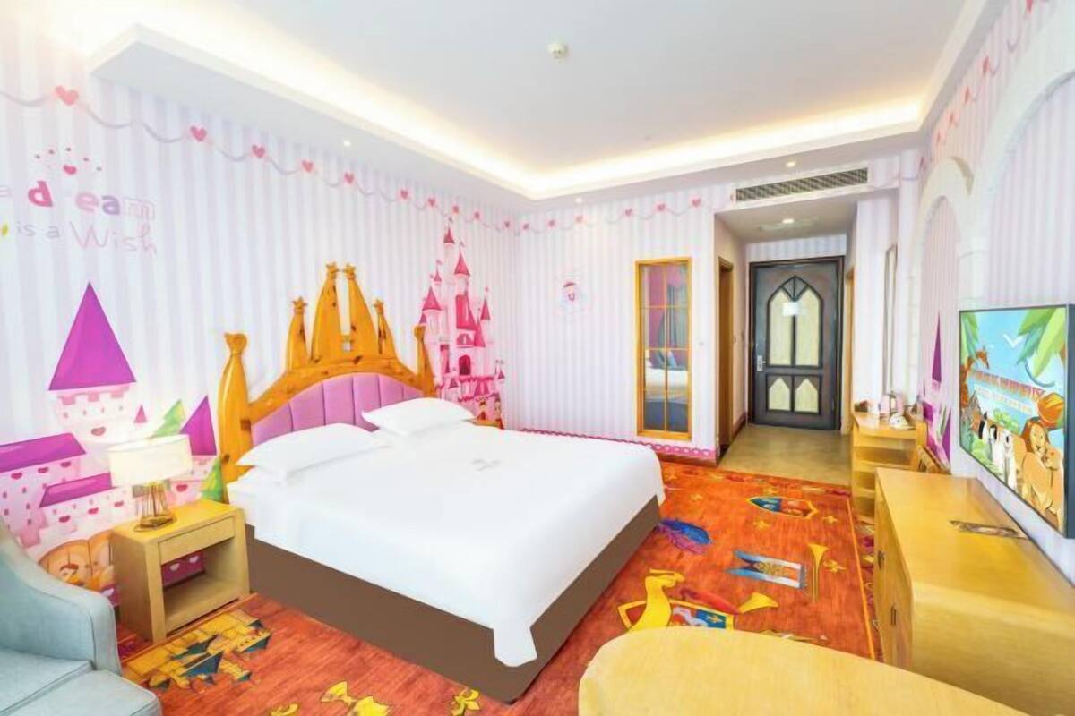 Une chambre d’enfant avec un lit, une table de chevet, une chaise et un téléviseur.