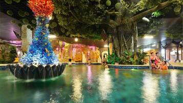 Piscina interna com uma fonte decorativa e um mural com tema tropical.