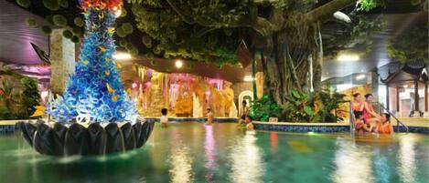 Una piscina interior con una fuente decorativa y un mural con temática tropical.