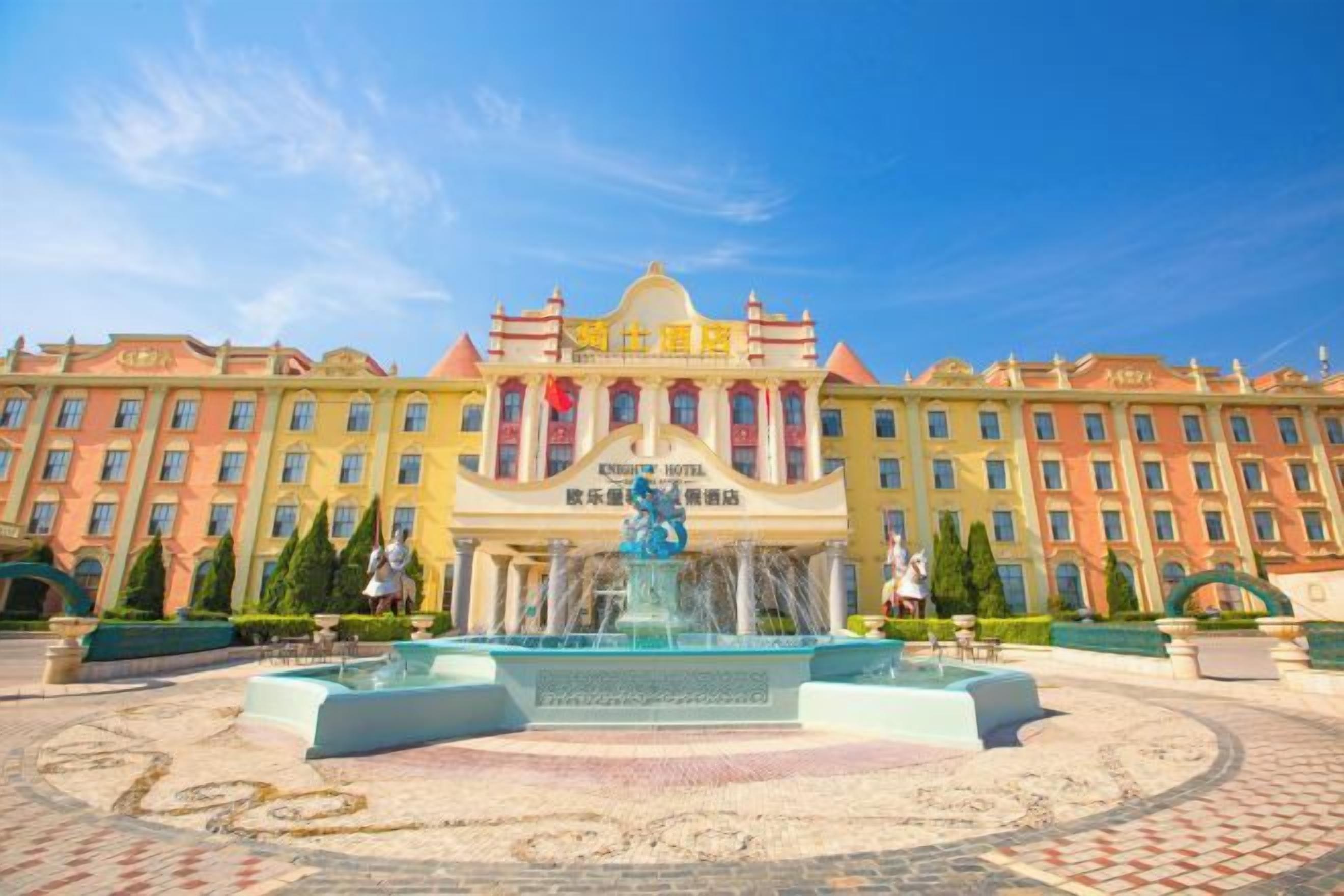 A hotel with a central fountain, multiple buildings, and a clear sky.