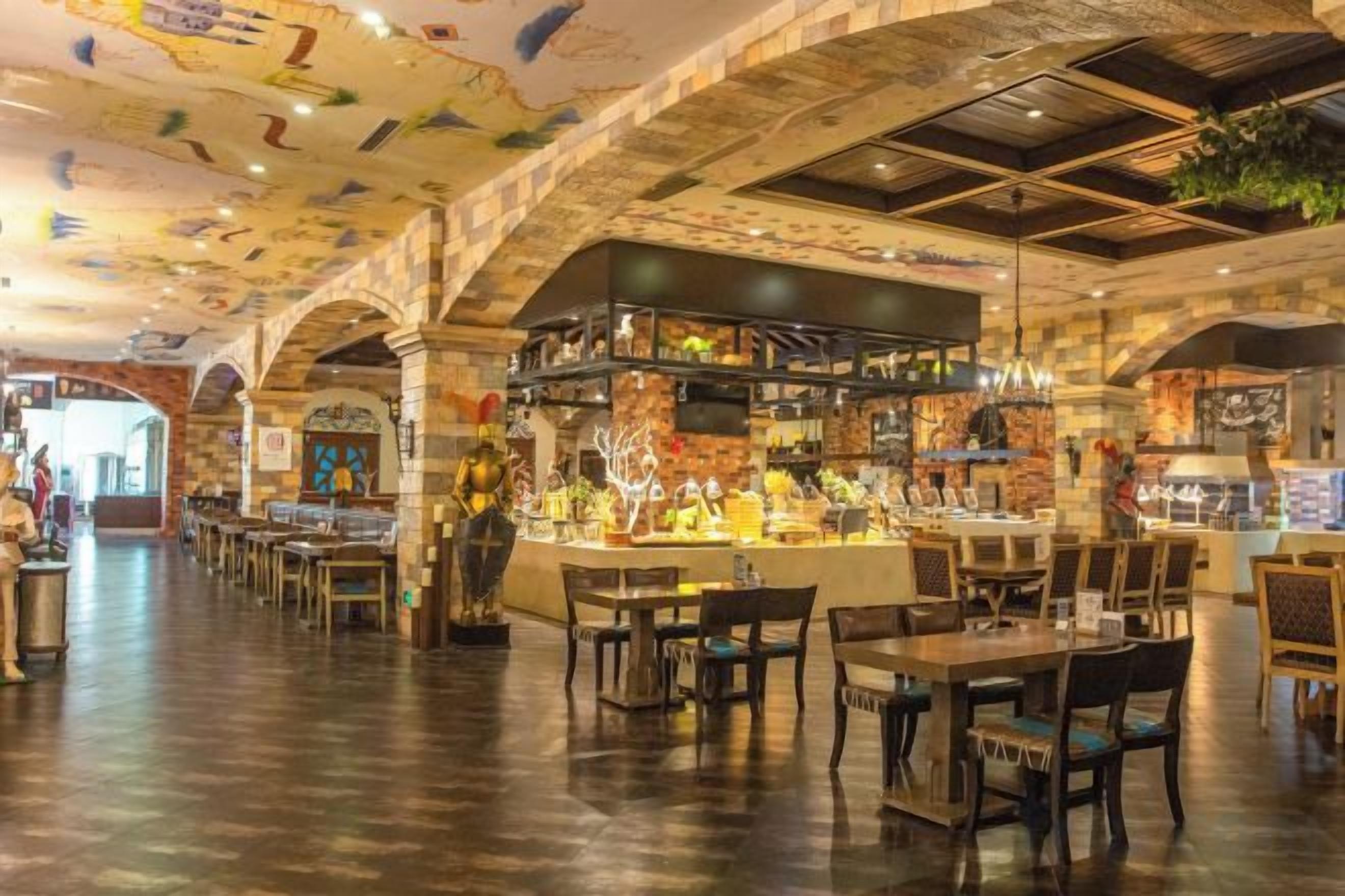 Um interior com área de bar, mesas de madeira e teto alto com detalhes decorativos.