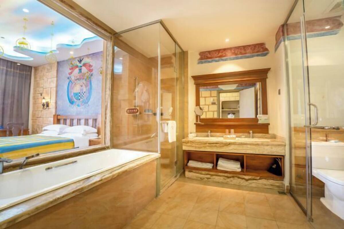 Une salle de bain moderne avec une douche à l’italienne en verre, un grand miroir et un meuble-lavabo en marbre.